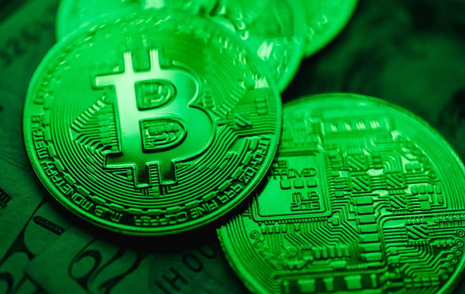 Gold-colored Bitcoin coins illuminated in green light, suggesting a theme of green crypto and greenwashing.