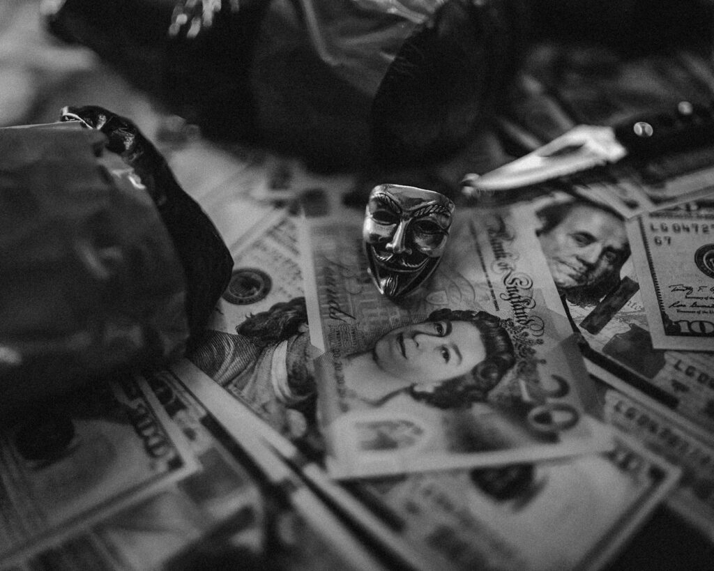 A black and white photo of various currencies with a small mask, suggesting the concept of money laundering.